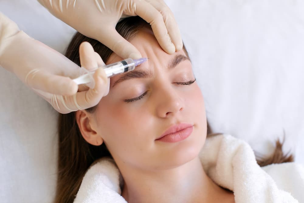 Close-up of a woman receiving BOTOX® injections in the forehead to lift the brows and smooth forehead lines during a non-surgical treatment
